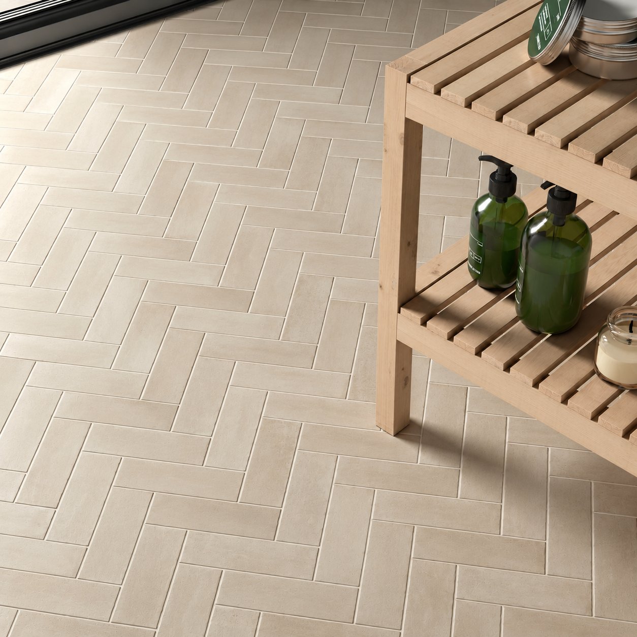 Beige tile floor laid in a herringbone pattern with a wooden bath bench in sunlight