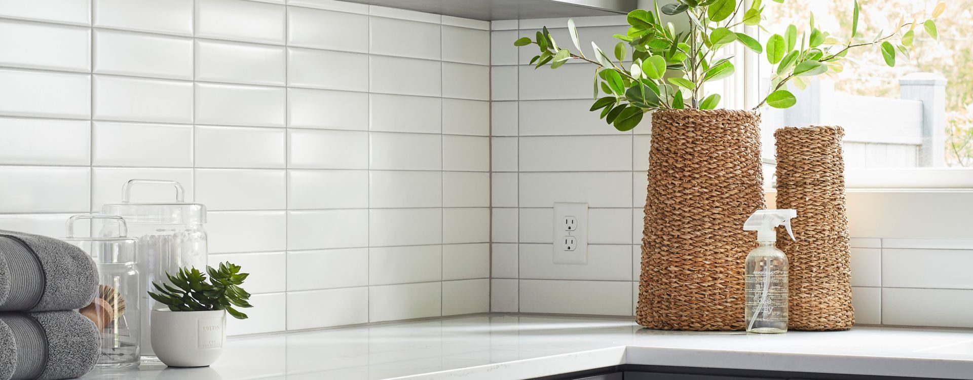 White rectangular tile kitchen backsplash in a straight stack, with an outlet cut into the tile